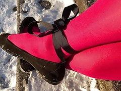 Crossdresser posing in pink pantyhose on snowy stairway