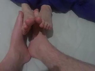 Two Friends Playing Footsies With Naked Feet On The Bed